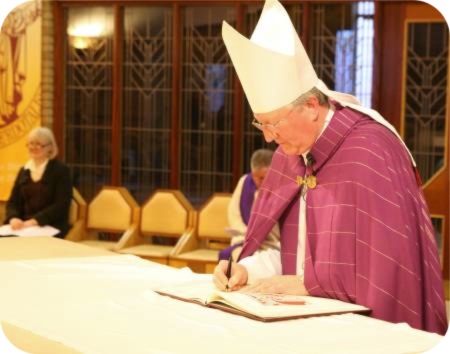 photo of Bishop Terry signing the Book of the Elect