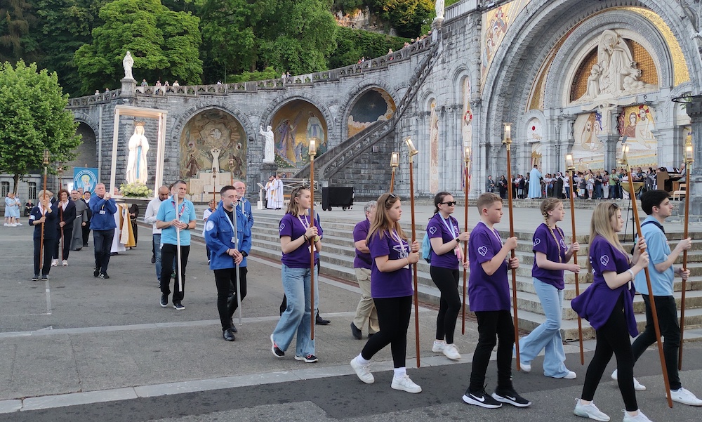 Some of our young people taking part in the Marian Torchlight Procession, while our brancardiers help carry the statue of Our Lady during Lourdes 2022 – Photo by Michael McGeary