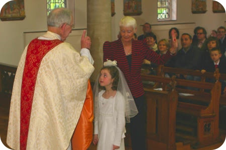 photo of Father White giving First Holy Communion to a girl
