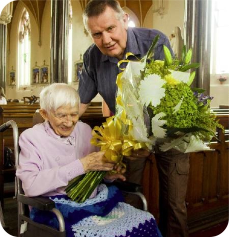 photo of Mary Boylen being presented with a bouquet
