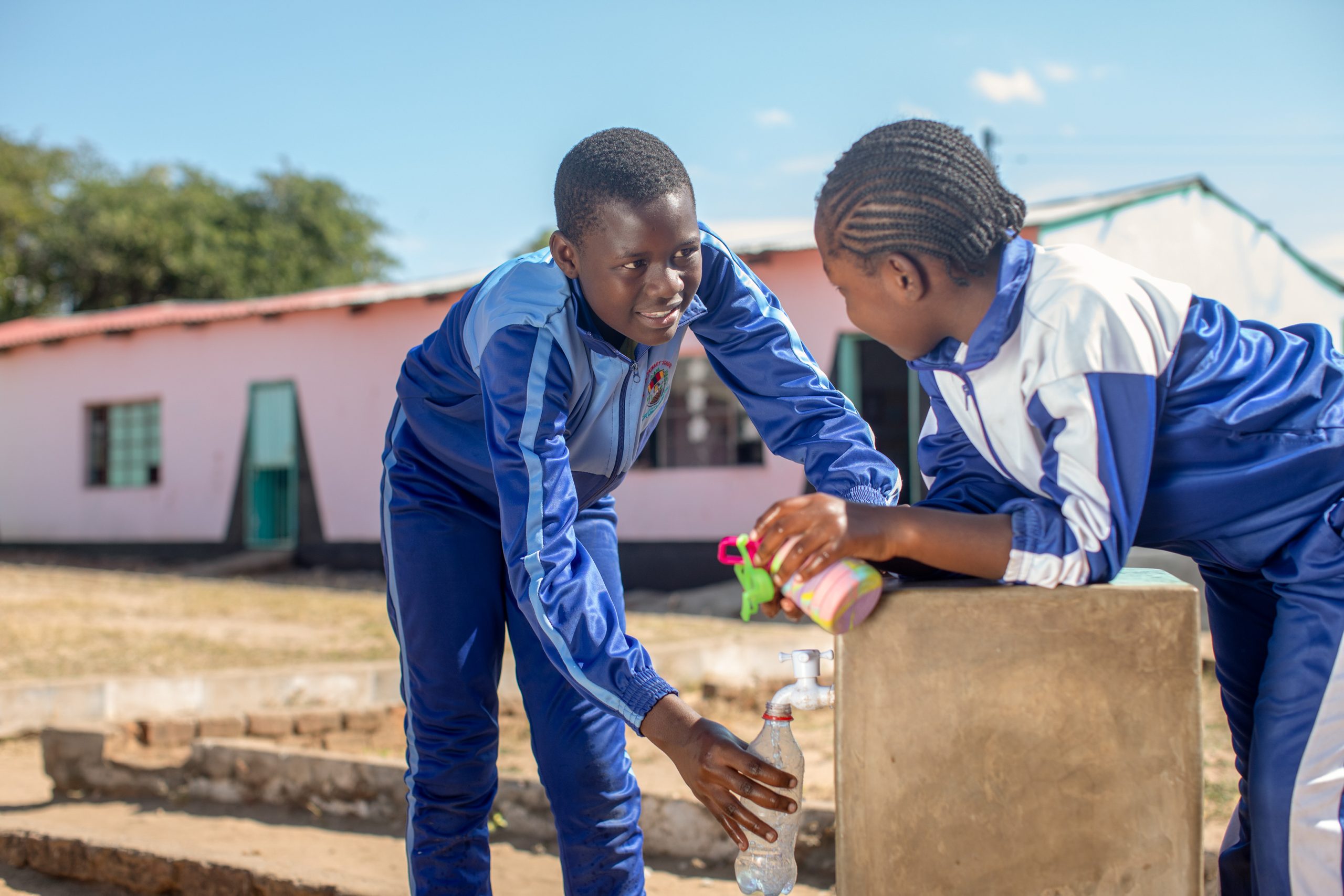 Kiki (right) and her friend harvest vegetables at their school, where a solar-powered piped water system is helping them grow food for nourishing school meals. Photo credit: Cynthia Matonhodze